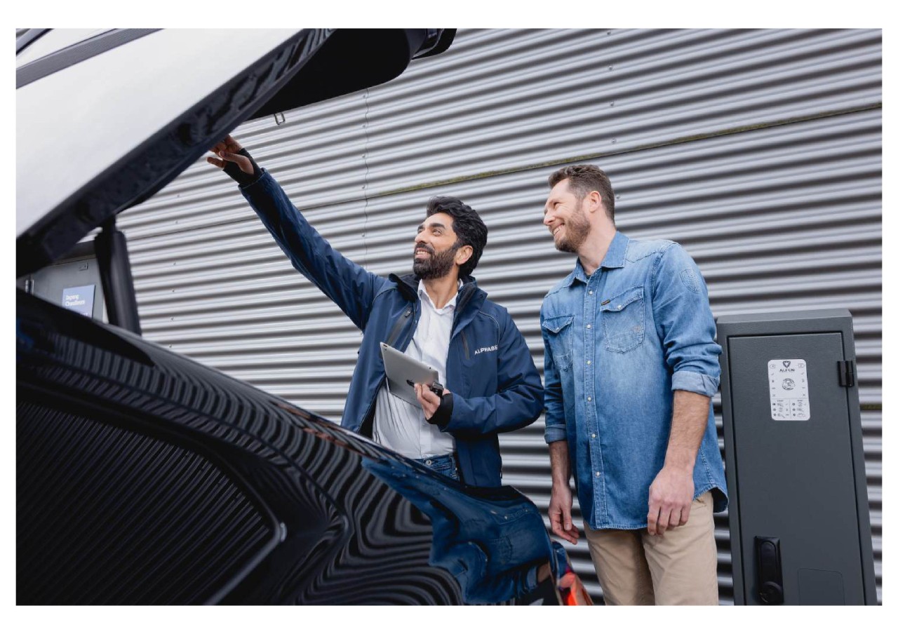 Two men looking under the car boot